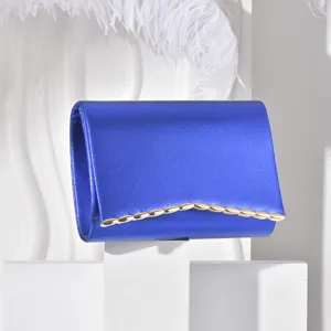 Blue evening clutch bag detail, stylish envelope design with gold wavy metal edge accent.