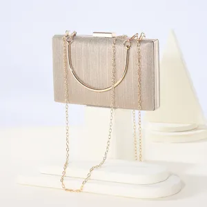 Detailed view of the champagne glitter evening clutch bag with metal chain and geometric prop.