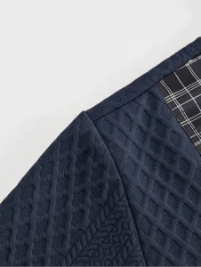 Men's sweatshirt fabric detail close-up, dark blue textured waffle knit with plaid patch.