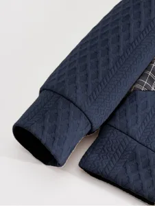 Detailed view of men's dark blue textured sweatshirt sleeve cuff with plaid contrast insert