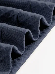 Detailed close-up of dark grey textured knit fabric showing soft folds and premium pattern.