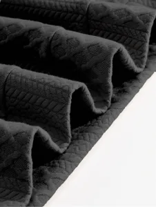Detailed view of dark textured fabric showing the fine knit quality and elegant texture of the apparel.