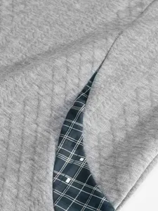 Close-up detail of men's grey quilted sweatshirt with stylish plaid inner lining and fine texture.