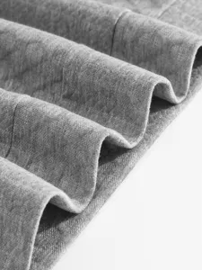 Close-up detail of grey sweatshirt fabric, showing soft texture and folded wave pattern.