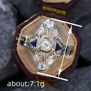 Primer plano detallado de un anillo antiguo de filigrana art déco con diamantes y zafiros azules.