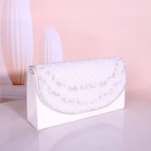 Close-up view of elegant white evening clutch bag adorned with pearls and sparkling rhinestones.