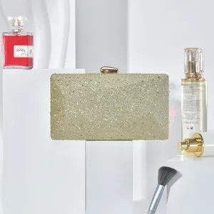 Detail view of the elegant gold glitter rhinestone evening clutch bag displayed on white pedestal.