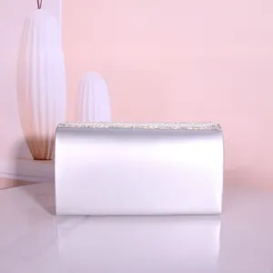 Detail view of silver satin evening clutch bag with sparkling rhinestones and pearl details.