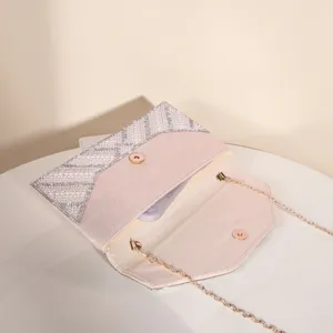 Close-up detail of the elegant rhinestone and pearl evening clutch bag with gold chain strap.
