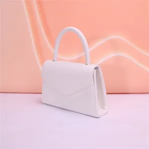 Dettaglio borsa da sera in pelle bianca, con elegante manico curvo e patta a busta.