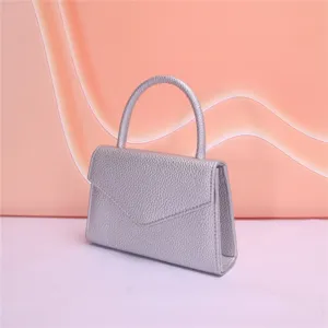 Dettaglio borsa da sera in pelle testurizzata argentata, elegante design con patta chic.