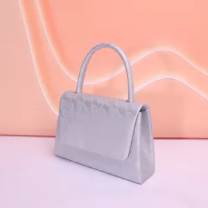 Sac à main de soirée en dentelle argentée élégant, détail avec une poignée unique.