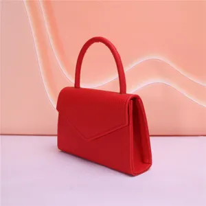 Dettaglio borsa da sera in pelle rossa, manico strutturato, design elegante e minimalista.