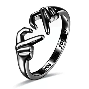 Detalle de anillo negro con gesto de corazón, grabado love you forever, accesorio diario elegante.