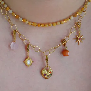 Dettaglio in primo piano di collana dorata con vari pendenti e collana di pietre preziose.