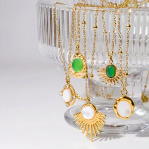 Close-up view of gold stainless steel layered necklaces with white shell and green jade pendants.