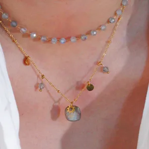Close-up detail of double layered natural stone necklace with gold chains and charms.