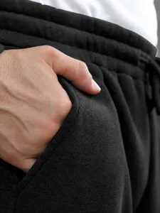 Detail view of black men casual sweatpants pocket, soft fleece fabric close up shot.