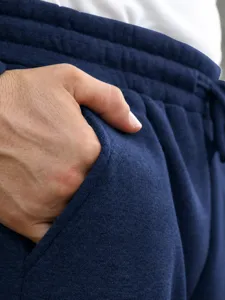 Men's casual pants detail view, showing soft blue knitted fabric, pocket and fine workmanship.