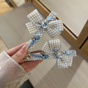 Detailed closeup of Korean style plaid bow hair clips with rhinestones and blue flower charms.