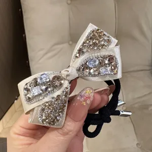 Champagne satin bow hair tie with sparkling crystals, elegant rhinestone ponytail holder.