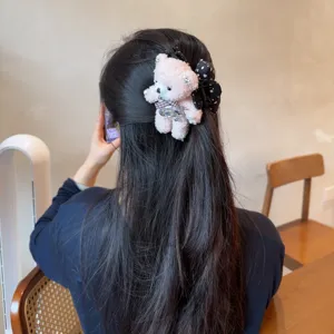 Nahaufnahme einer niedlichen flauschigen rosa Bären Haarklammer mit karierter Schleife.