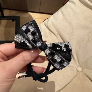 Close-up view of a black crystal bow hair tie with sparkling rhinestones and elegant design.