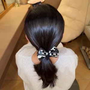 Close-up detail of a sparkling rhinestone bow hair tie, elegant crystal black hair accessory.