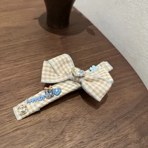 Checkered bow hair clip detail view, featuring blue trim, sparkling rhinestones and sweet style.