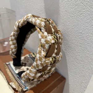 Detail view of retro houndstooth braided headband with chic leather and gold chain accents.