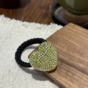 Close-up detail of a sparkling yellow rhinestone heart hair tie with black band for elegant styling.