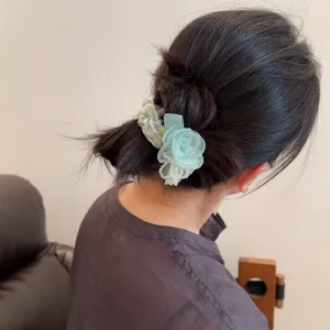 Close-up of the delicate floral scrunchie with lace edge worn on hair, sweet style detail view.