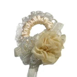 Elegant champagne scrunchie with lace trim, crystal beads, and fabric flower for sweet hair styling.