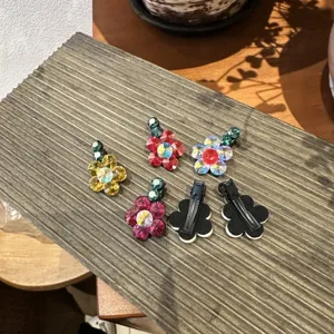 Λεπτομερής όψη από λαμπερά τσιμπιδάκια μαλλιών με λουλούδια στρασ, μπροστά και πίσω.