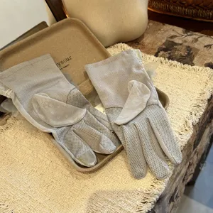 Vue détaillée de gants courts de protection solaire en dentelle grise avec charmants pompons.