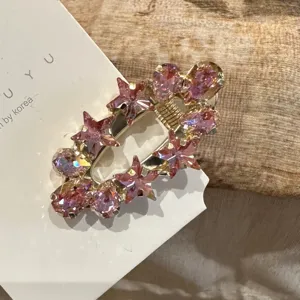 Close-up of pink crystal star hair clip detail, sparkling rhinestone duckbill clip accessory.