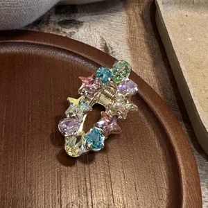Detailed close-up of colorful crystal star hair clip showcasing sparkling rhinestones and metal base.