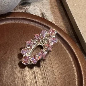 Close-up detail of the sparkling pink crystal rhinestone hair clip on a wooden tray surface.