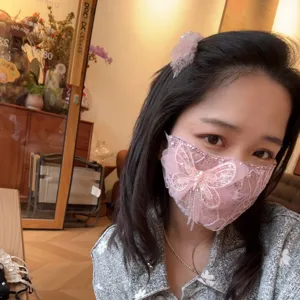 Dettaglio della maschera facciale rosa in pizzo con farfalla strass e nappa di cristallo.
