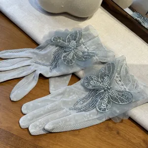 Vue détaillée de gants en dentelle grise avec papillon en perles et pampilles.