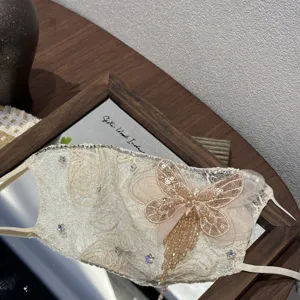 Vista dettagliata della maschera in pizzo di lusso con strass e nappa a farfalla di perline.