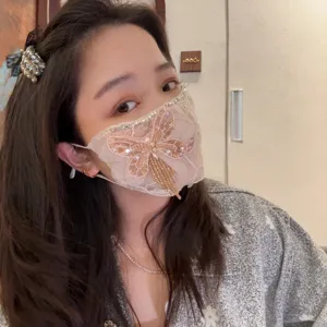 Dettaglio maschera facciale regolabile coreana di lusso con strass e farfalla con paillettes.