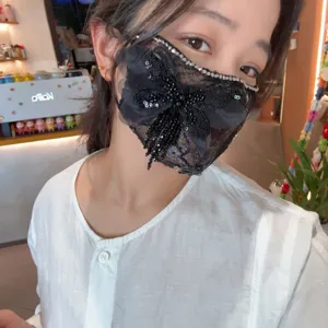 Primo piano della maschera in pizzo con paillettes scintillanti, strass e fiocco in cristallo.