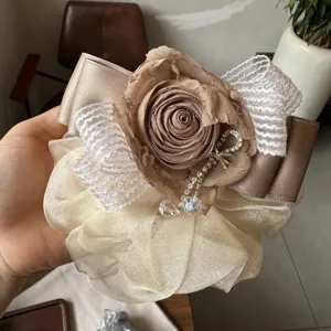 Primo piano dell'elastico per capelli in organza con rosa sfumata, fiocco e ciondolo di cristallo.