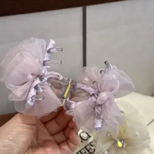 Nahaufnahme des eleganten lila Organza-Blüten-Haarklammers mit zarten Perlen und Strass.