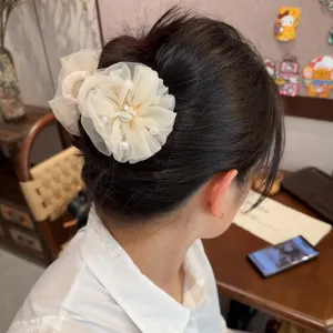 Nahaufnahme der eleganten, beigen Netzblumen-Haarklammer mit Perlen, perfekt im Haar gestylt.