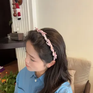 Detail shot of the pink bow pearl headband, showing close-up texture, beads, and stylish wear.