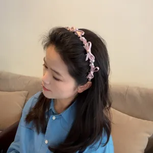 Close-up view of a pink bow pearl headband worn by model, sweet everyday hair accessory.