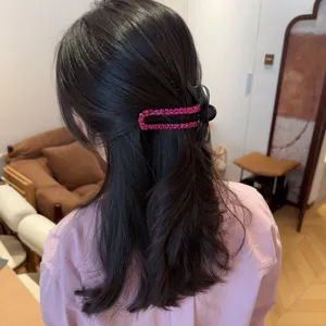 Primo piano dettagliato di una molletta per capelli rosa brillante con un elegante fiocco nero.