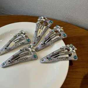 Close-up detail of glittering triangle hair clips with starfish and rhinestones, lucky text.